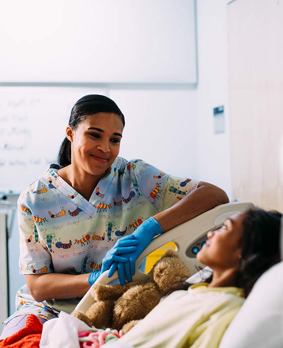 A nurse looks after a young child in a hospital bed